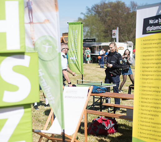 HSZG cube and banner on the festival meadow at the Europafest. Two policemen play table tennis in the background.