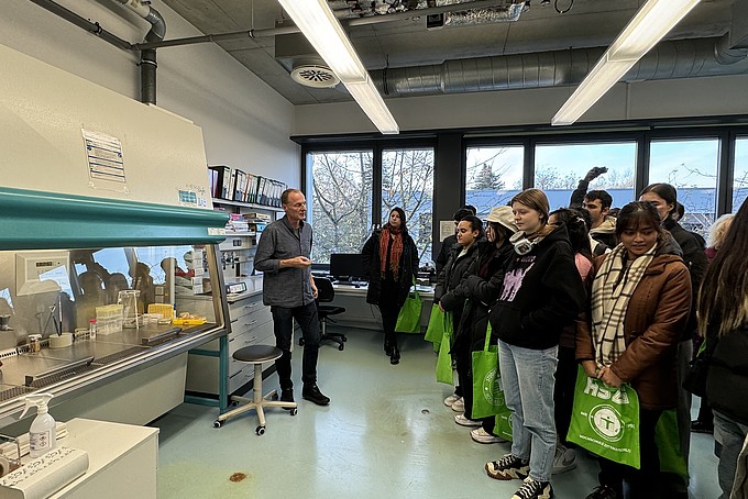 Prof. Dr. Thomas Wiegert steht in einem Labor der HSZG und spricht zu einer Gruppe internationaler Studieninteressierter des Rahn Studienkollegs Leipzig. Die Teilnehmenden stehen in einer Gruppe und hören aufmerksam zu. Im Hintergrund sind Laborgeräte und Arbeitsmaterialien zu sehen.